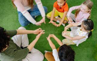 Children and adults seated together on grass
