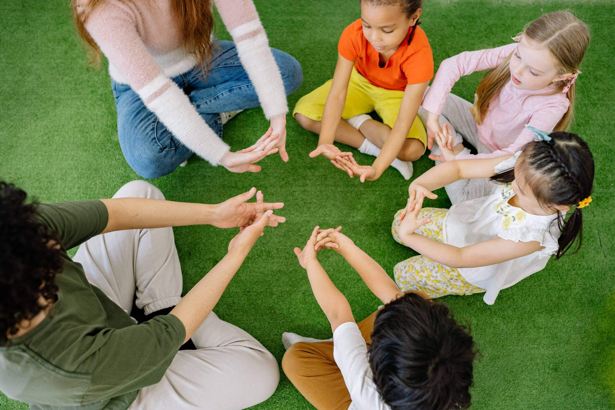 Children and adults seated together on grass