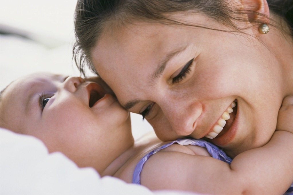 Parent smiling while holding a young child